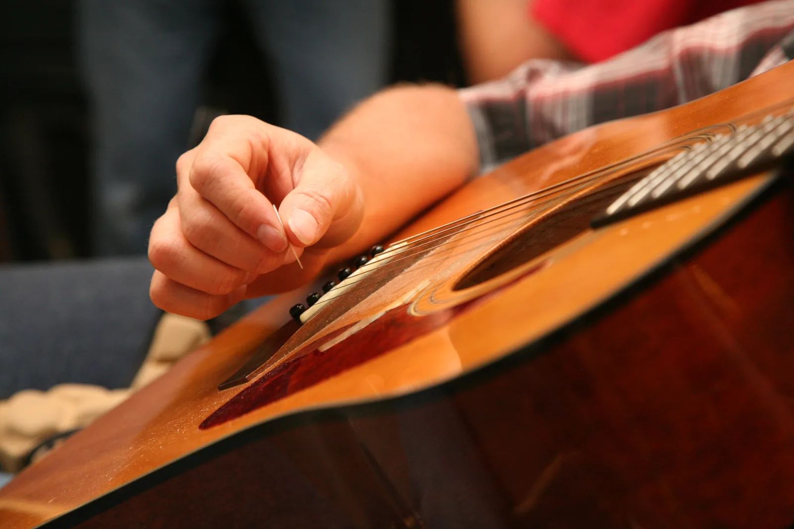 A guitarist's right hand picking the strings of a flamenco guitar above its tapping plate